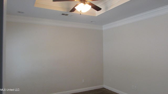 spare room with a raised ceiling, visible vents, dark carpet, ornamental molding, and baseboards