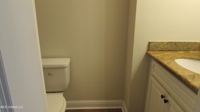 bathroom featuring toilet, vanity, and baseboards