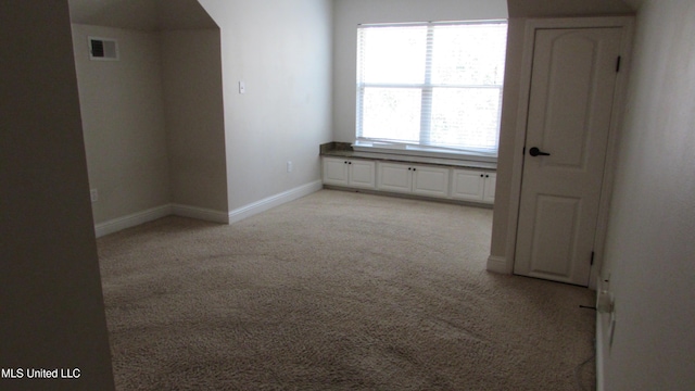 unfurnished room with visible vents, light carpet, and baseboards