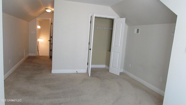 unfurnished bedroom featuring lofted ceiling, a closet, carpet, and baseboards