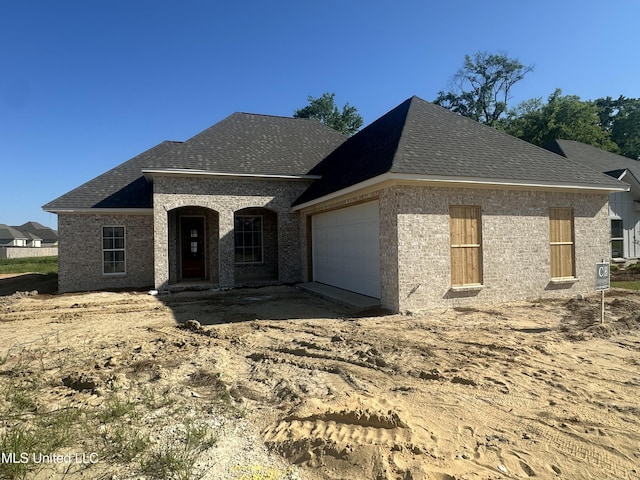 406 Butternut Dr, Canton, MS 39046 - french country inspired facade featuring brick siding, an attached garage, and roof with shingles