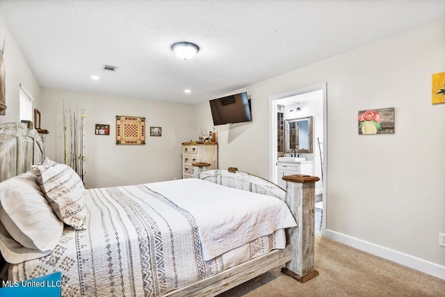 carpeted bedroom with connected bathroom and a textured ceiling