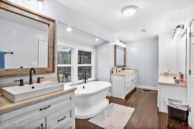 bathroom with a bath, wood-type flooring, vanity, and a textured ceiling