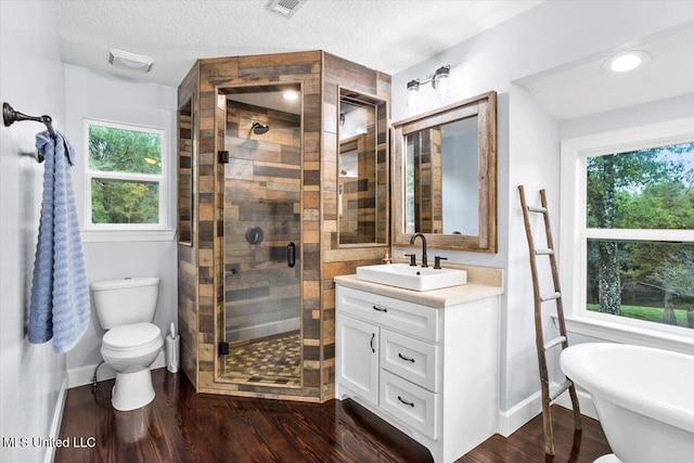 full bathroom with a wealth of natural light, hardwood / wood-style floors, and a textured ceiling