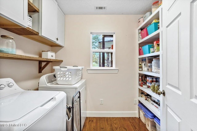 laundry room with cabinets, a textured ceiling, washer and dryer, and dark hardwood / wood-style floors