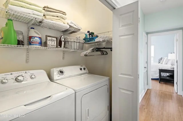 washroom with washing machine and clothes dryer and light hardwood / wood-style floors