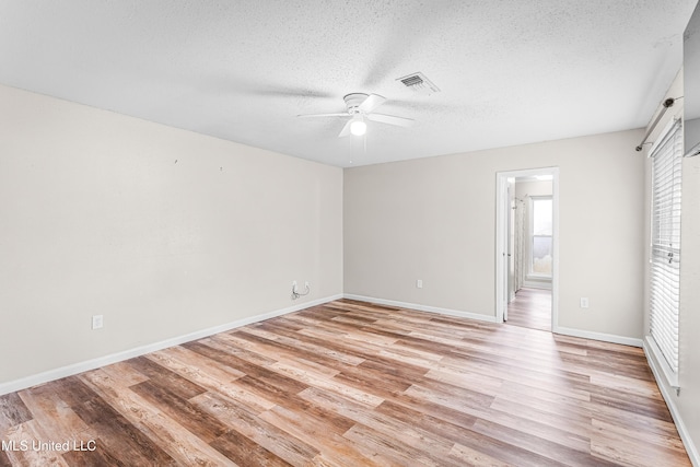 unfurnished bedroom featuring light wood-type flooring, baseboards, a textured ceiling, ensuite bath, and visible vents