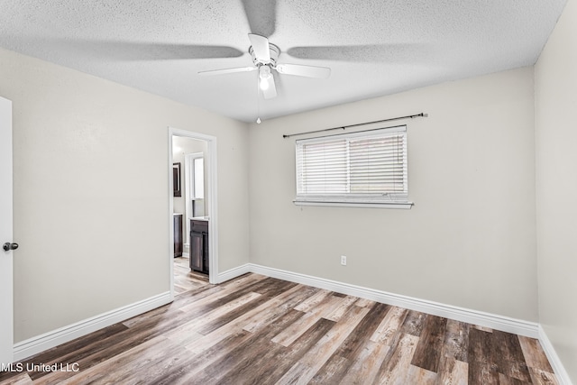 unfurnished room featuring baseboards, a textured ceiling, wood finished floors, and a ceiling fan