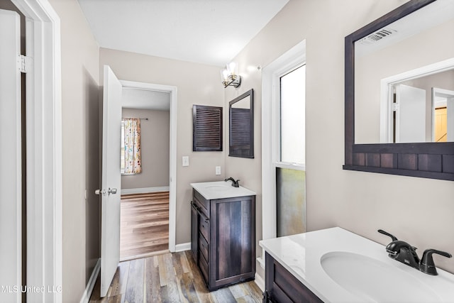 bathroom featuring wood finished floors, a sink, two vanities, and visible vents