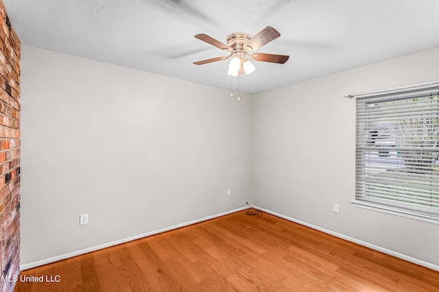 unfurnished room with baseboards, wood finished floors, ceiling fan, and a textured ceiling
