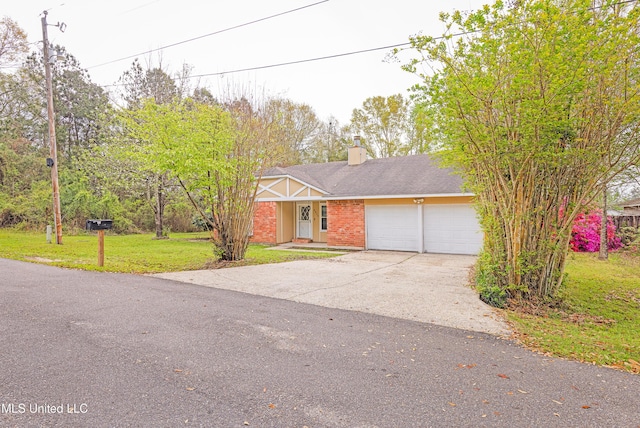 view of front of house featuring an attached garage, a chimney, concrete driveway, a front yard, and brick siding