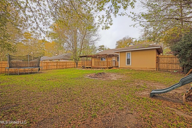 view of yard featuring a fenced backyard, a playground, a deck, and a trampoline