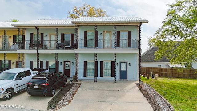 64 Oak Alley Ln, Long Beach, MS 39560 - rear view of property featuring fence, a balcony, metal roof, and a lawn
