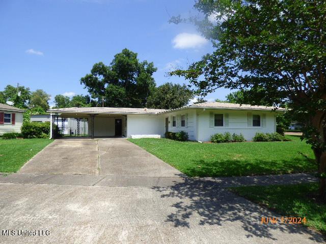 ranch-style home featuring a carport and a front yard