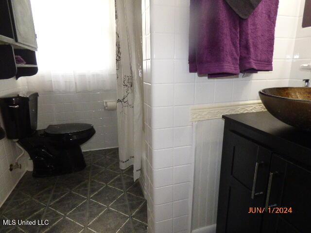bathroom with tile walls, toilet, tile patterned floors, and vanity