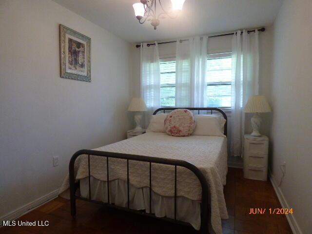 bedroom featuring a notable chandelier and dark hardwood / wood-style flooring