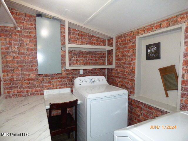 washroom featuring brick wall and washer / clothes dryer