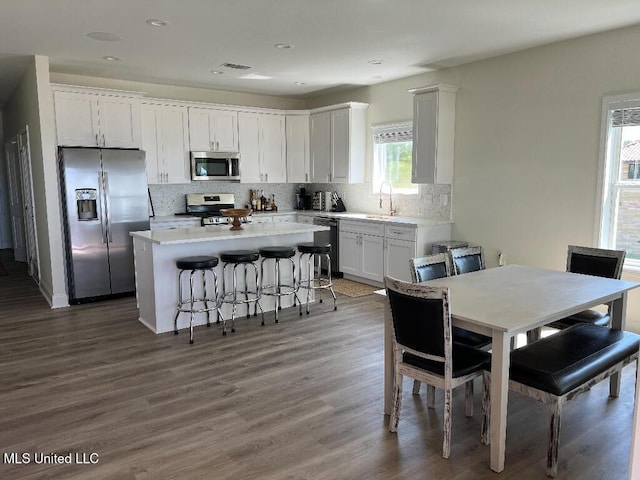 kitchen featuring white cabinets, dark hardwood / wood-style floors, tasteful backsplash, a kitchen island, and stainless steel appliances