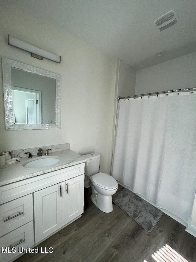 bathroom with wood-type flooring, vanity, and toilet