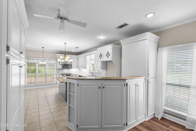 380 Green Acres Dr, Canton, MS 39046 - kitchen featuring a chandelier, stainless steel microwave, white cabinets, open shelves, and a peninsula