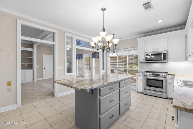 380 Green Acres Dr, Canton, MS 39046 - kitchen featuring appliances with stainless steel finishes, white cabinets, a chandelier, a kitchen island, and ornamental molding