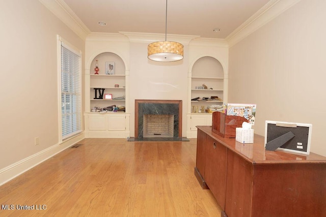 living room with a premium fireplace, built in features, crown molding, light wood finished floors, and baseboards