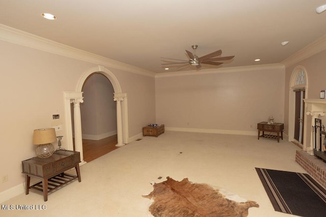 unfurnished living room featuring a ceiling fan, ornate columns, light carpet, arched walkways, and ornamental molding