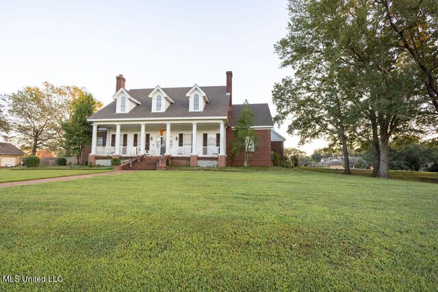 cape cod house featuring covered porch, a front lawn, and a chimney