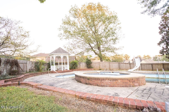 view of pool featuring a hot tub, a water slide, a gazebo, and a patio