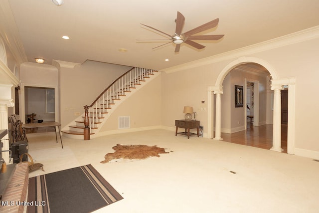 interior space featuring decorative columns, ceiling fan, carpet flooring, and ornamental molding