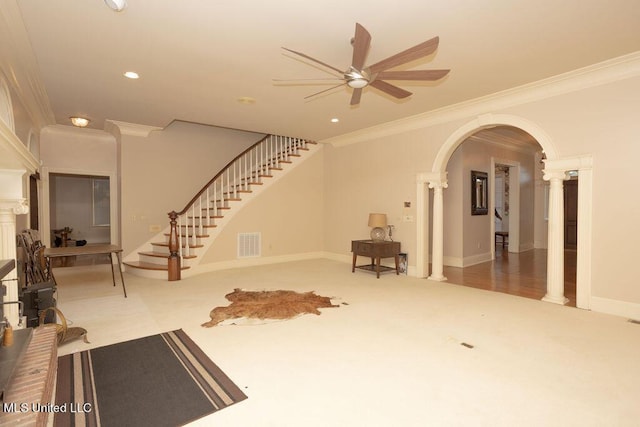 unfurnished living room with ornate columns, a ceiling fan, ornamental molding, arched walkways, and carpet