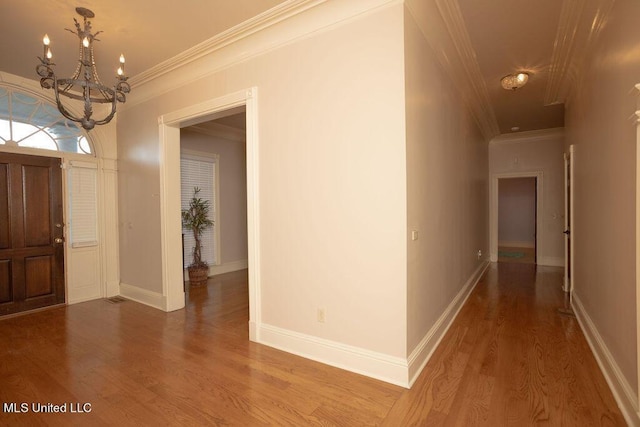 entrance foyer with ornamental molding, a chandelier, wood finished floors, and baseboards