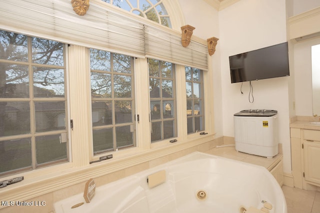 bathroom with vanity, plenty of natural light, a tub to relax in, and washer / clothes dryer