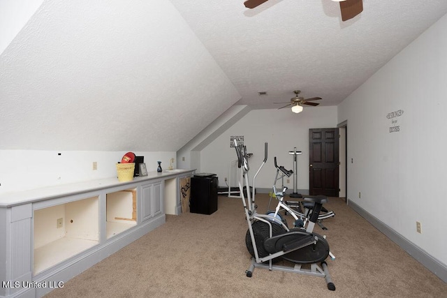 exercise area featuring a ceiling fan, a textured ceiling, light carpet, lofted ceiling, and baseboards