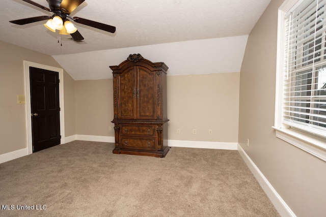 unfurnished bedroom with light carpet, a textured ceiling, ceiling fan, and vaulted ceiling