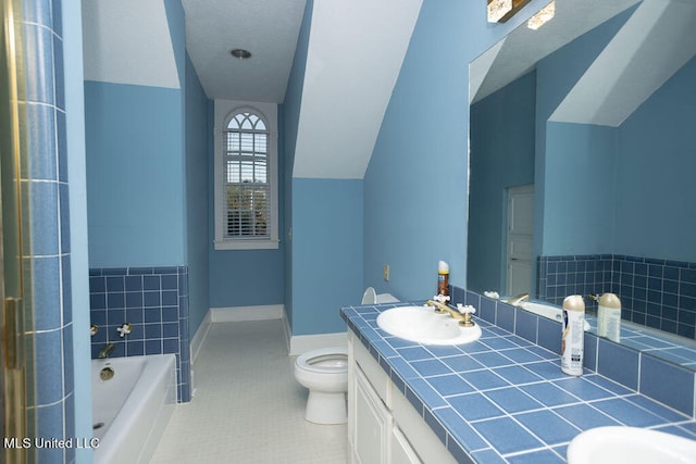 bathroom with vaulted ceiling, toilet, a washtub, vanity, and tile patterned floors