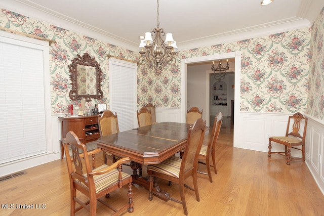 dining room with light hardwood / wood-style floors, crown molding, and a notable chandelier