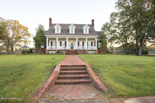 cape cod home with covered porch, a chimney, and a front yard