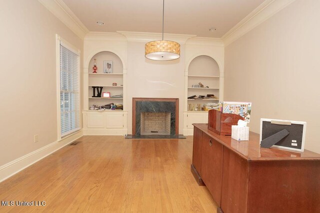 living room with a premium fireplace, built in features, crown molding, light wood finished floors, and baseboards