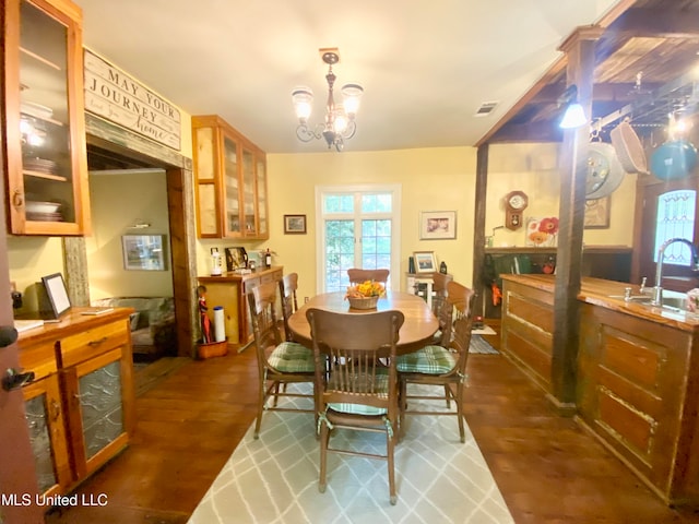 dining space with a chandelier, dark wood-type flooring, and sink