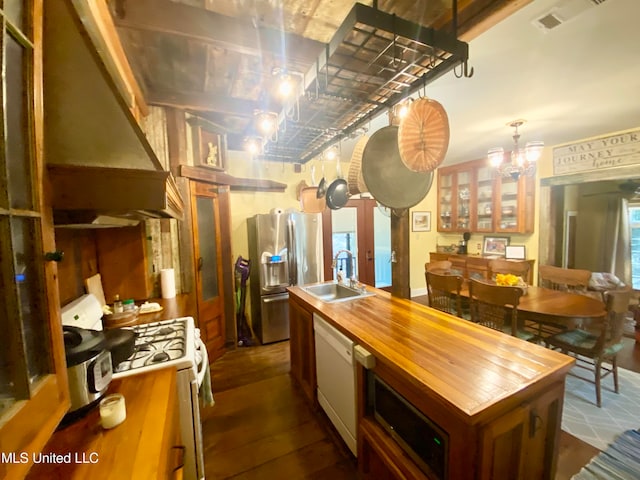 kitchen featuring white appliances, sink, an island with sink, dark hardwood / wood-style flooring, and pendant lighting