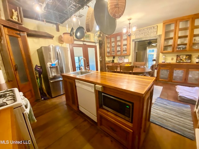 kitchen with sink, stainless steel appliances, decorative light fixtures, dark hardwood / wood-style floors, and a kitchen island with sink