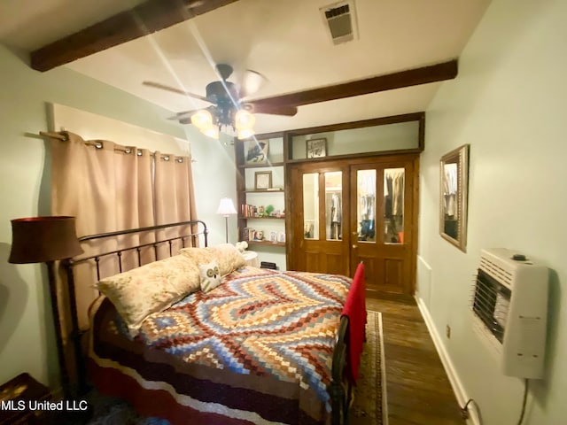 bedroom with dark hardwood / wood-style flooring, beamed ceiling, heating unit, and ceiling fan