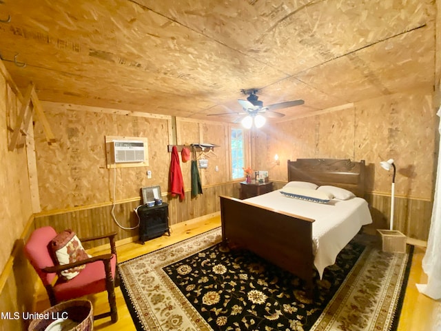 bedroom with a wall mounted AC, hardwood / wood-style flooring, and wood walls