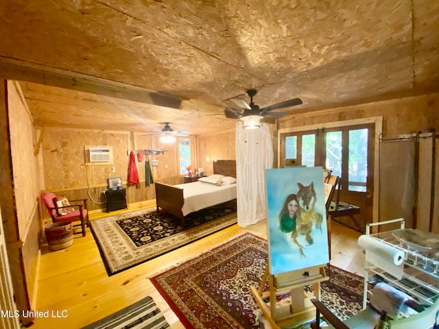 bedroom with hardwood / wood-style floors, a wall mounted AC, french doors, and wooden walls