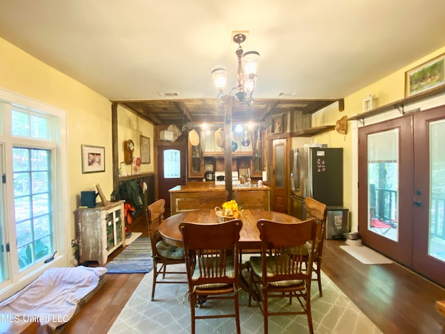 dining room with french doors, wood-type flooring, and an inviting chandelier