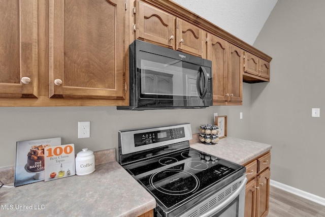 kitchen featuring stainless steel electric stove, light wood-type flooring, and a textured ceiling