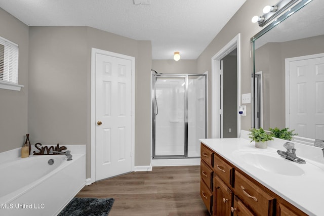 bathroom with hardwood / wood-style floors, vanity, separate shower and tub, and a textured ceiling