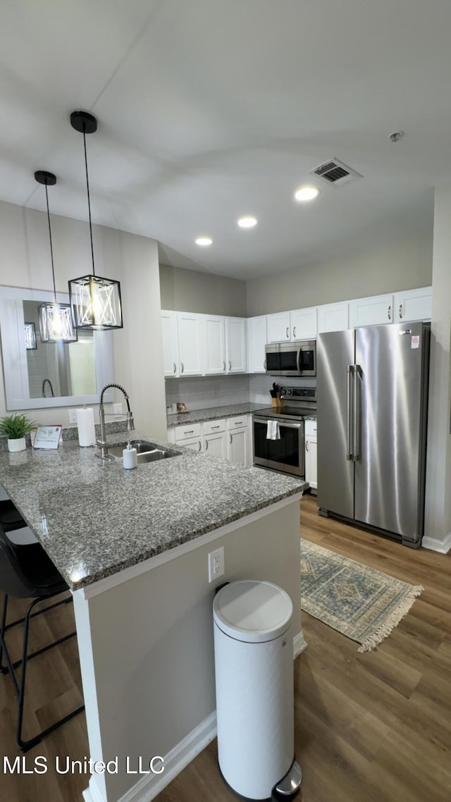 204 Town Center Dr Unit 31, Oxford, MS 38655 - kitchen with stainless steel appliances, a sink, a breakfast bar, white cabinets, and dark stone countertops