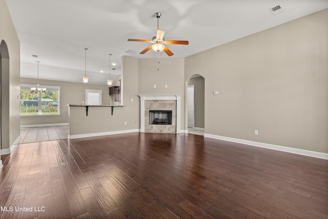 unfurnished living room with a fireplace, wood-type flooring, and ceiling fan with notable chandelier